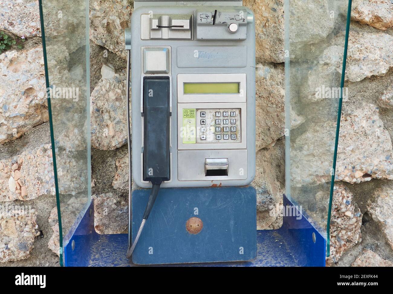 Close cropped shot of an old coin- and card-operated public telephone set on a rocky wall in Frigiliana, Malaga, Spain Stock Photo