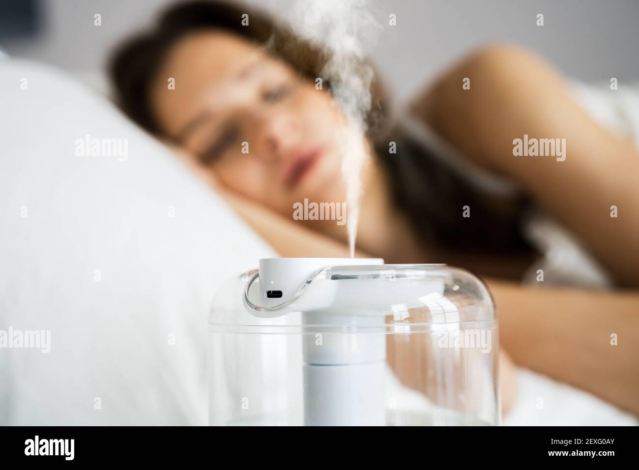 Home Air Humidifier Device In Bedroom Near Woman Sleeping Stock Photo