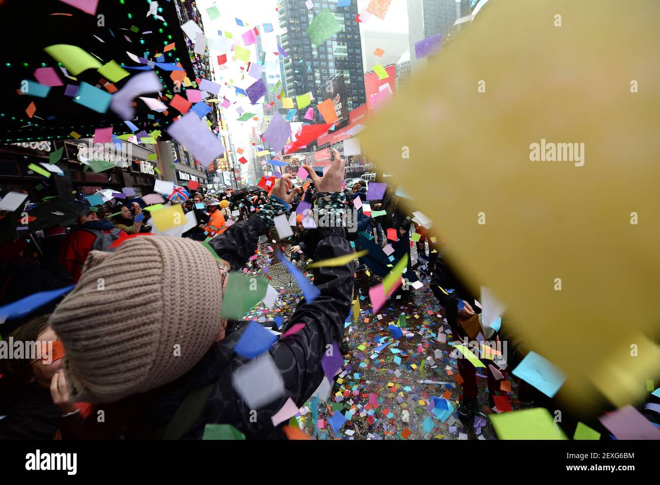 A woman reaches out to catch confetti as it is being thrown from atop ...