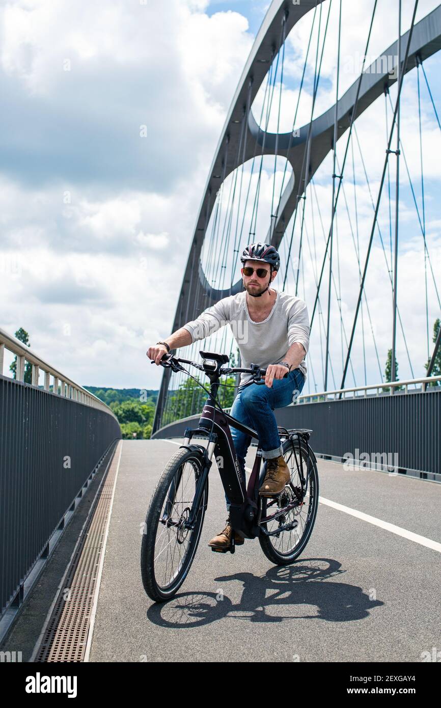 Cyclist on electric bike is crossing the East Harbour Bridge in Frankfurt am Main, Hessen, Germany. Stock Photo