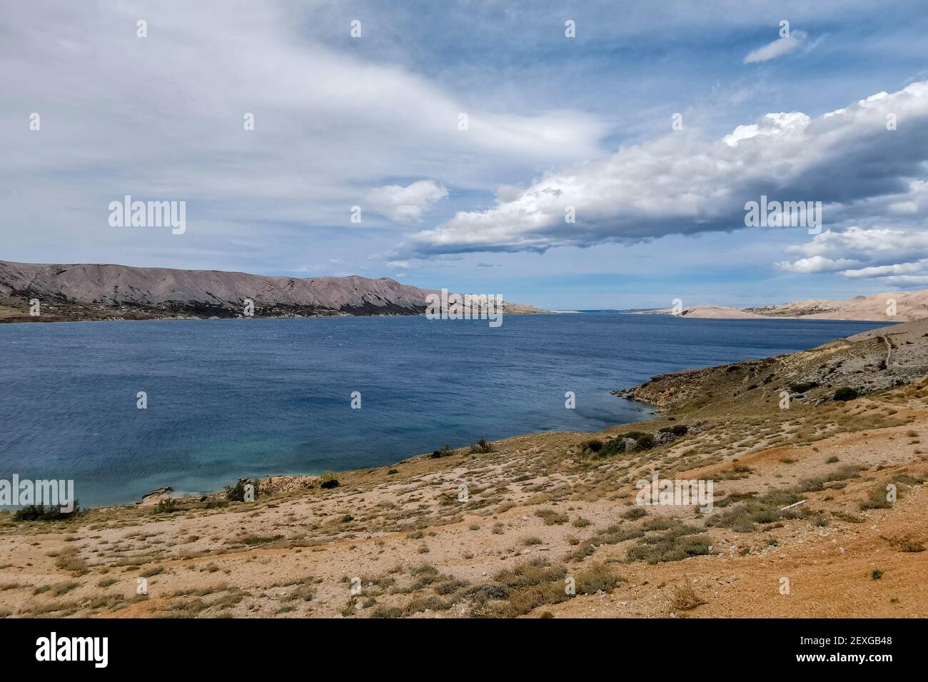 A beautiful view of the sea surrounded by rocky cliffs under a cloudy ...