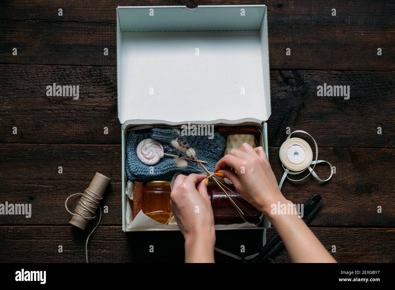 Care box, package ideas. Female hands fold a care box with sweets and ...