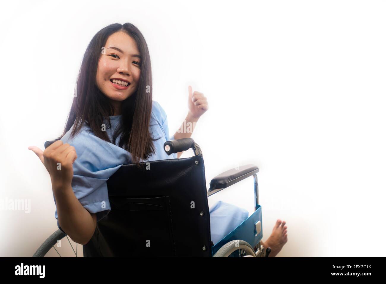 Portrait Of Young Happy And Positive Asian Chinese Woman In Hospital Gown Sitting On Wheelchair 3763