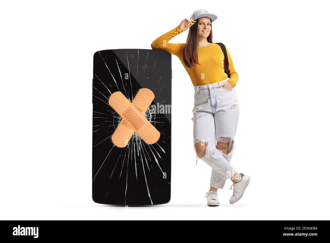 Full length portrait of a girl leaning on a big smartphone with cracked screen and bandage isolated on white background Stock Photo