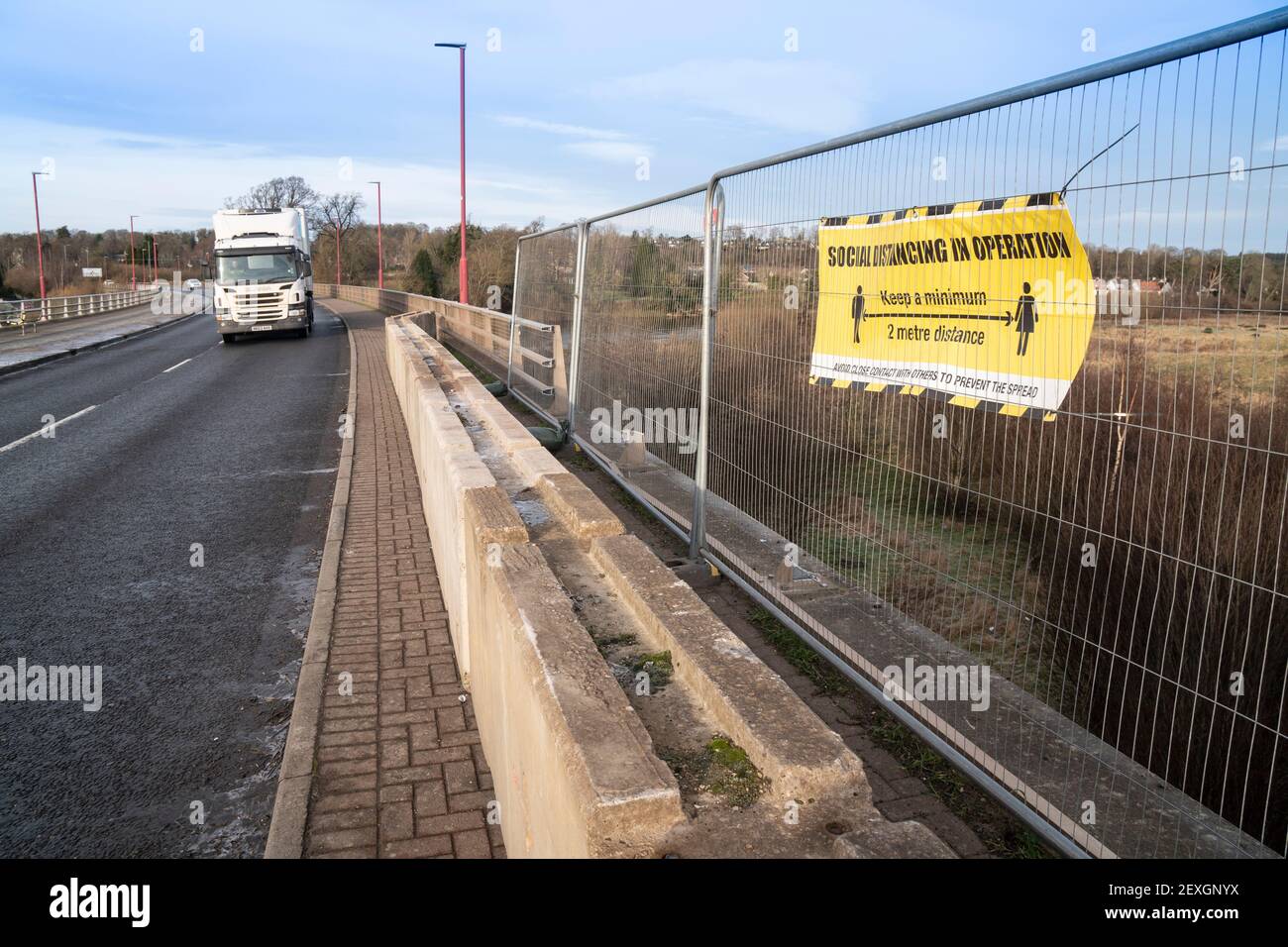A sign says keep 2m apart for Covid safety, but the footpath is closed as a car smashed through the barrier of a bridge in Kelso, Scotland Stock Photo