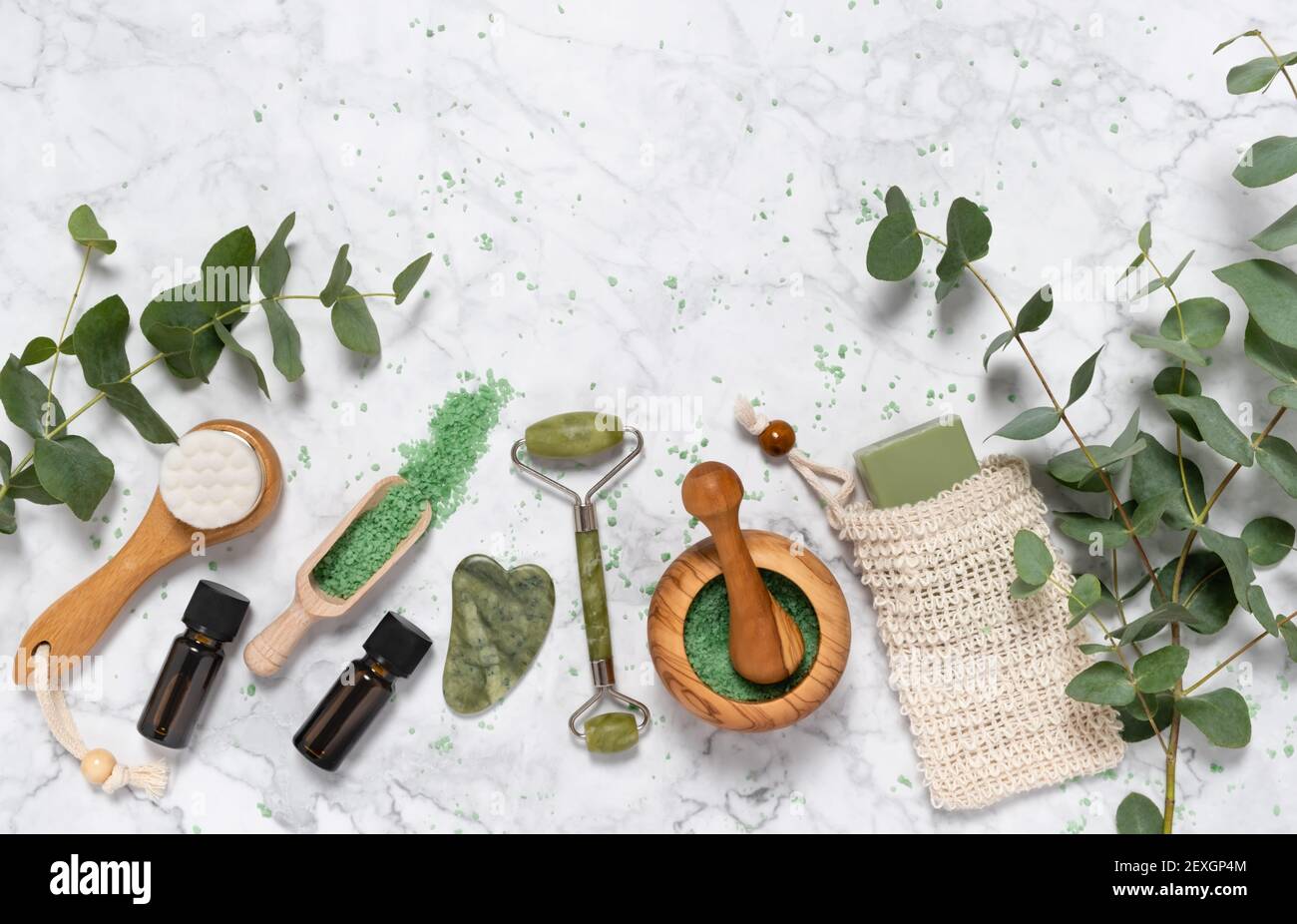 Natural skin care and aromatherapy with eucalyptus essential oil bottles, bath salt, beauty jade roller, gua sha on marble. Spa, wellness, massage and Stock Photo