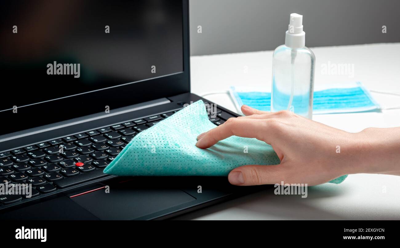 Female hands disinfecting laptop keyboard using Disinfectant spray
