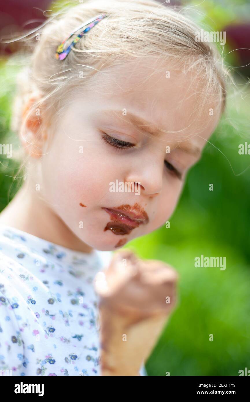 Chocolate kiss - very cute little girl eating choc Stock Photo