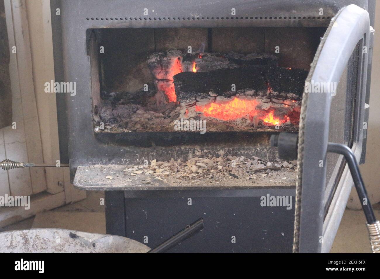 Adding wood into a wood stove during the cold winter months Stock Photo