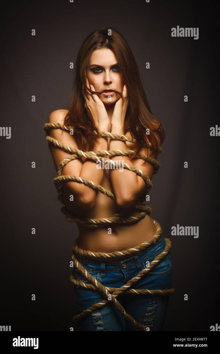 Brunette woman bound with rope prisoner in jeans Stock Photo