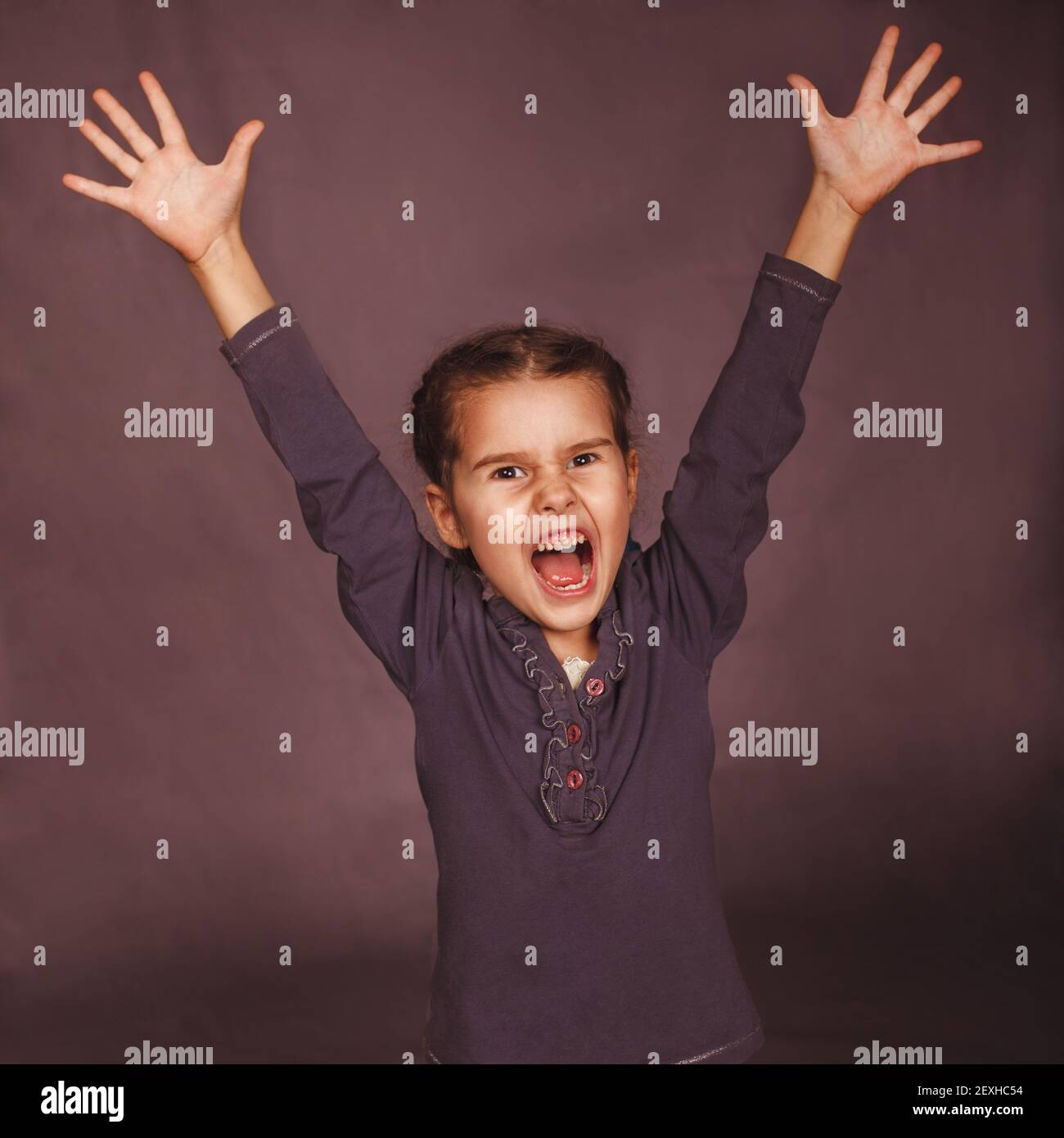 Little child girl opened her mouth screaming mouth lifted up on Stock Photo