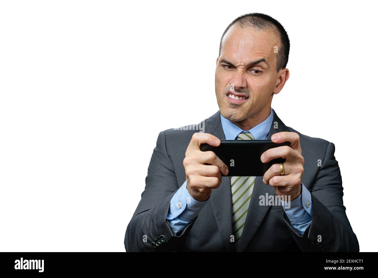 Mature man with suit and tie, playing on his smartphone and making a funny angry face. Stock Photo