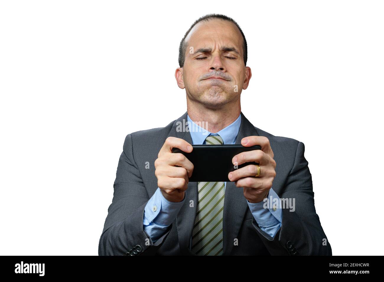 Mature man with suit and tie, holding his smartphone horizontally, breathing out through his nose and with his eyes closed. Stock Photo