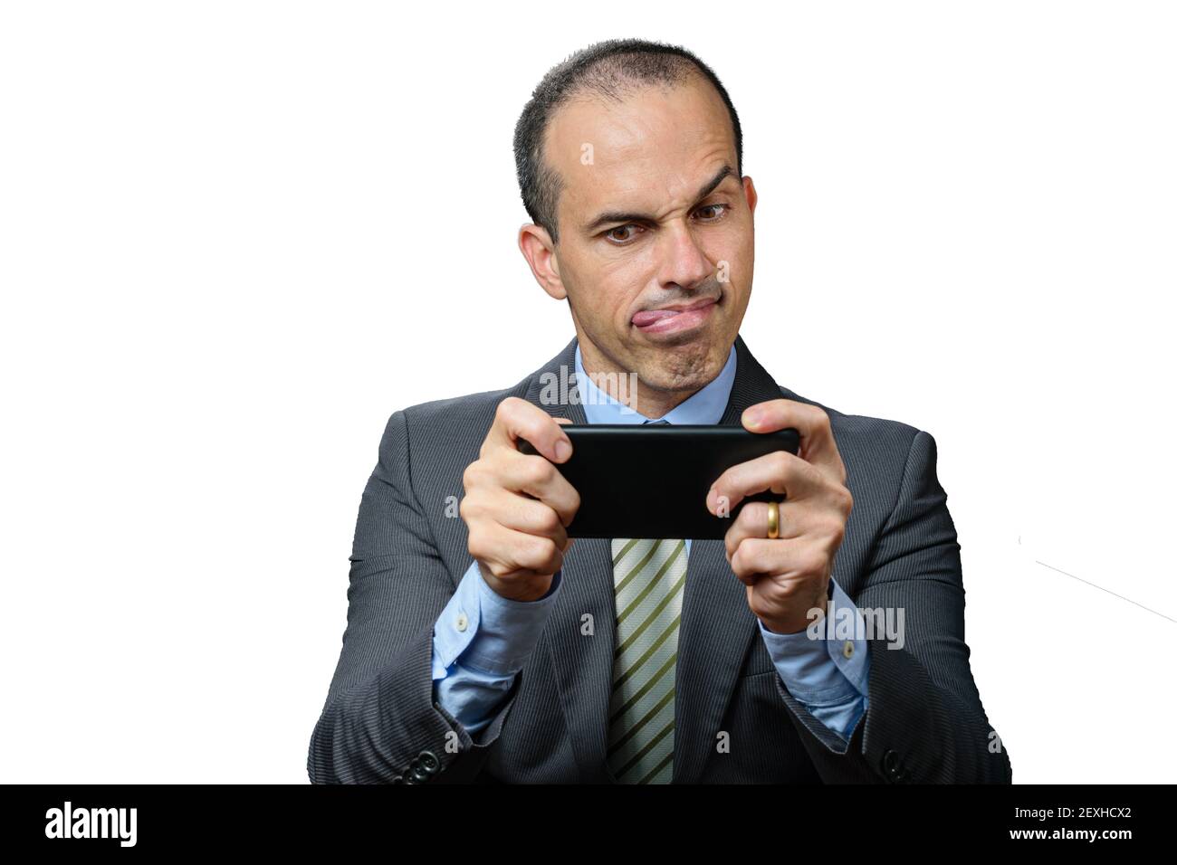 Mature man with suit and tie, biting his tongue, raised eyebrow and holding smarthphone horizontally. Stock Photo