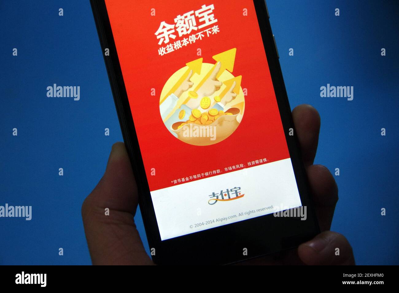 FILE--A man uses YuEbao, the fund management platform under Alipay of  Alibaba Group, on his smartphone in Ji'nan city, east China's Shandong  province, 5 November 2014. Yuebao, China's largest money market fund