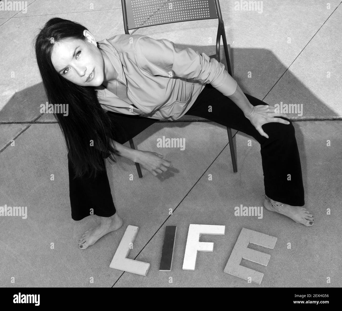 Attractive woman on concrete Above the Word Life in Block Letters Stock Photo
