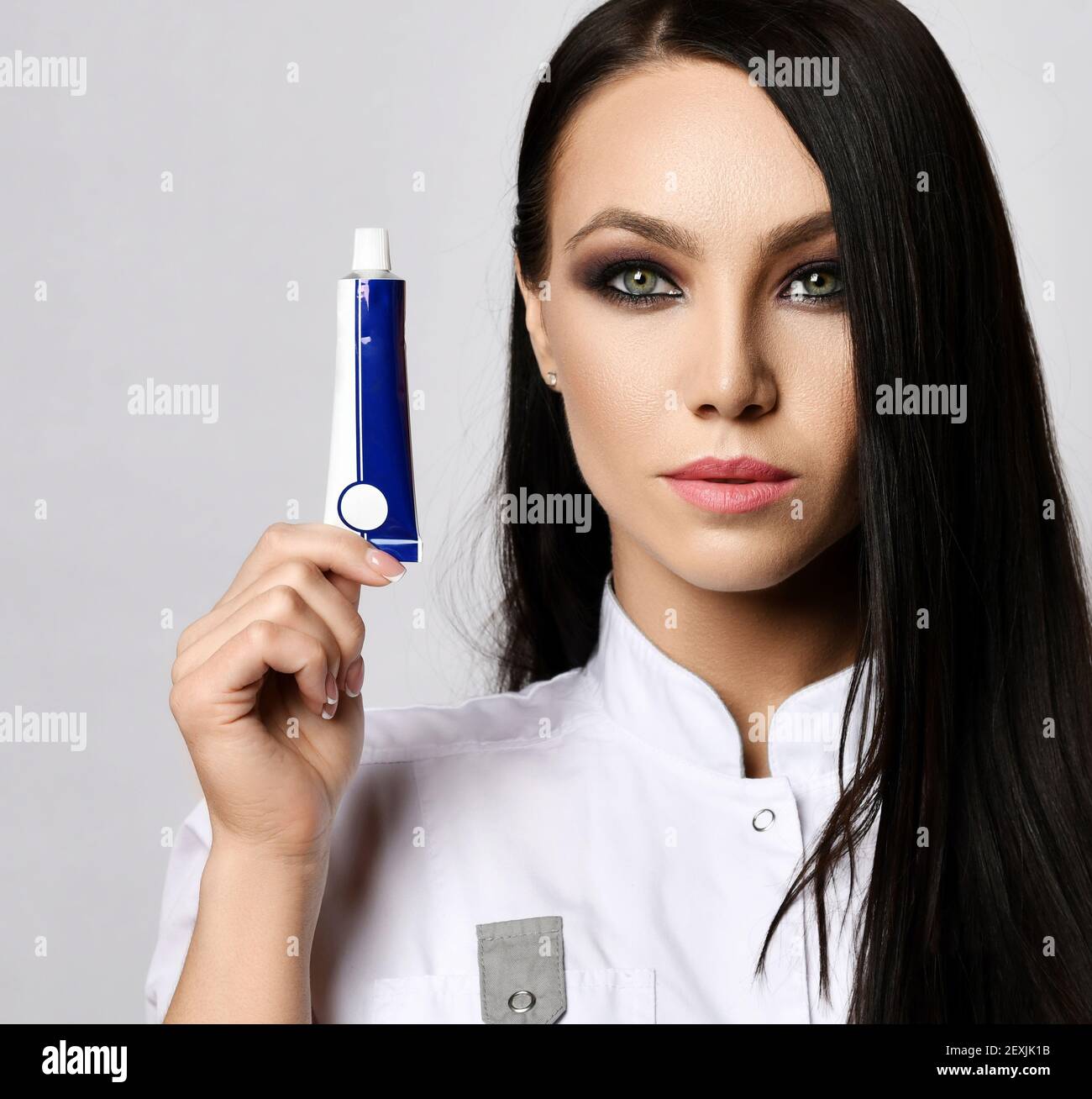 Portrait of woman doctor cosmetologist in medical gown holding tube with special remedy cream gel. Copy space Stock Photo