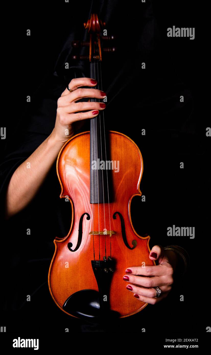 Female Violinist Holds Bow Across Saturated Musical Violin Acoustic Instrument Stock Photo