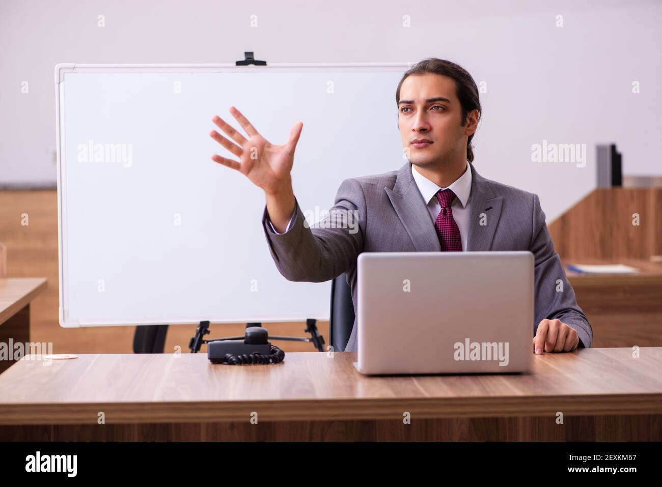 Young handsome business trainer in the office during pandemic Stock Photo