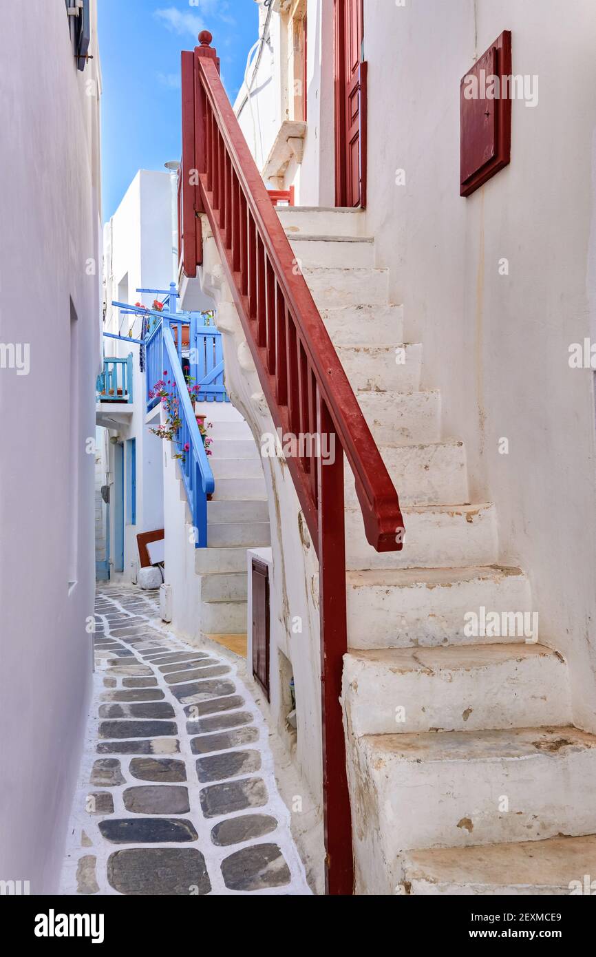 Traditional narrow cobbled streets, beautiful alleyways of Greek island towns. White houses, flower pots, balconies, stairs and doors. Mykonos, Greece Stock Photo