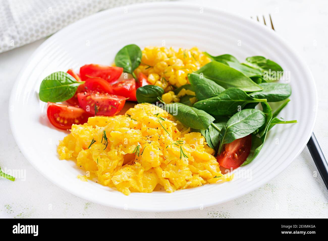 Breakfast. Scrambled eggs with cherry tomatoes, spinach  and corn. Stock Photo