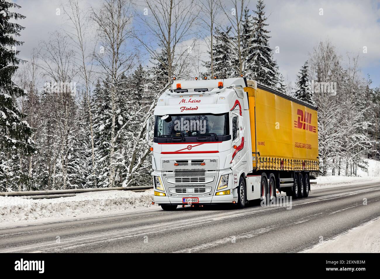 Beautifully customised white Volvo FH truck M. Leino pulls DHL freight trailer on highway 52 on cold day of winter. Salo, Finland. February 12, 2021. Stock Photo