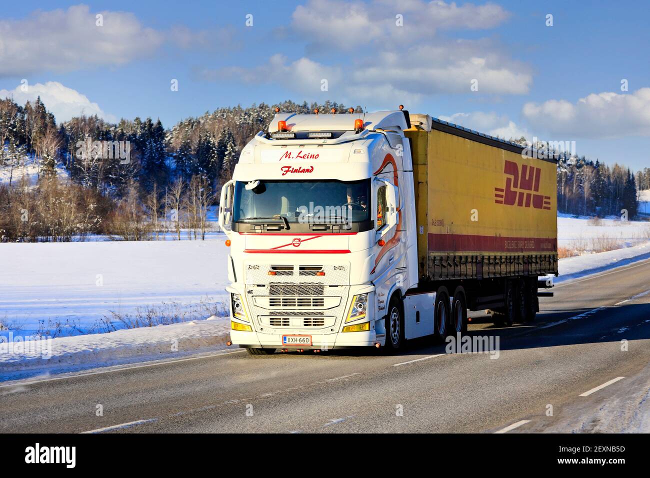 Beautifully customised white Volvo FH truck M. Leino pulls DHL freight trailer on highway 52 on sunny day of winter. Salo, Finland. February 11, 2021. Stock Photo