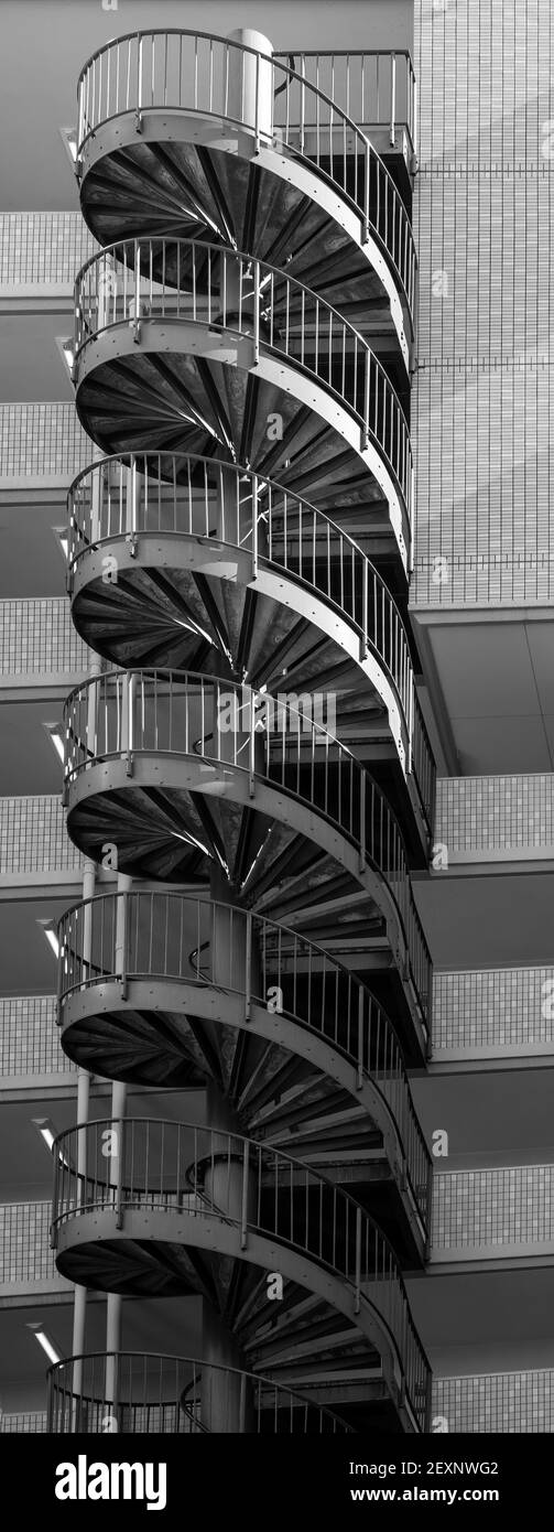 Spiraling, metal staircase, ascends and descends on the outside of an apartment building. Stock Photo