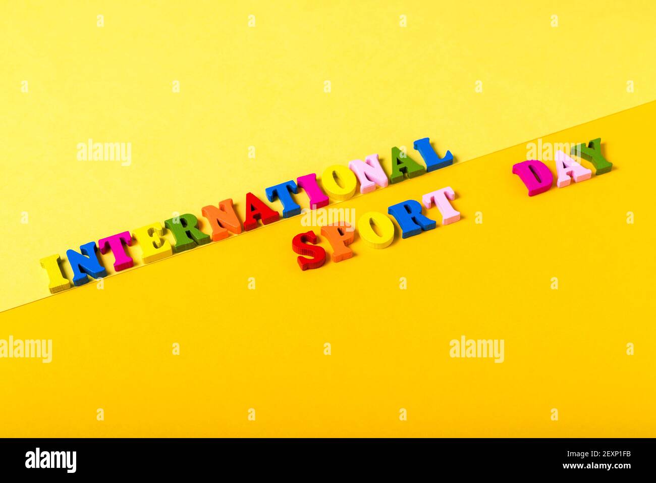 Wooden letters International Sports Day on a yellow background. The concept of the development of sports in the world, the holiday on April 6. Stock Photo