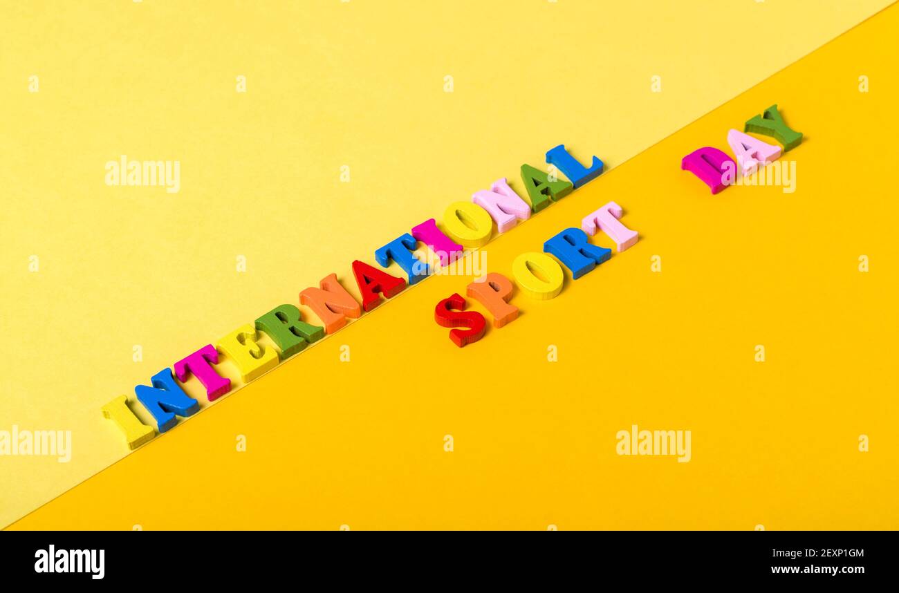 Wooden letters International Sports Day on a yellow background. The concept of the development of sports in the world, the holiday on April 6. Stock Photo