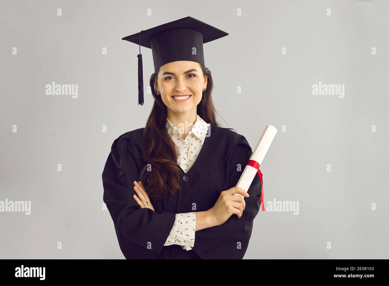 Studio portrait of happy smart college graduate holding her diploma and smiling at camera Stock Photo