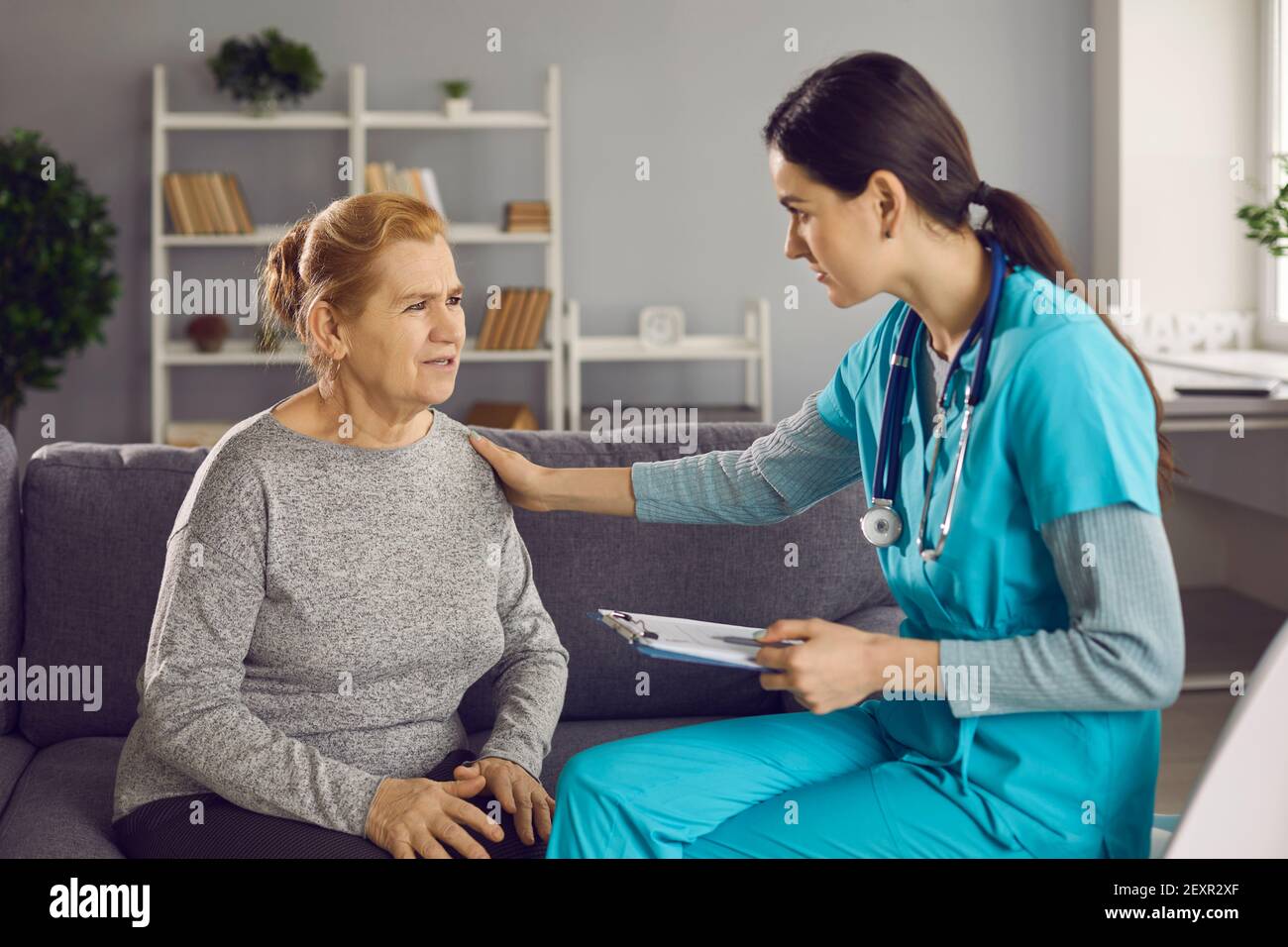 Worried senior woman talking to doctor and telling her about her health concerns Stock Photo