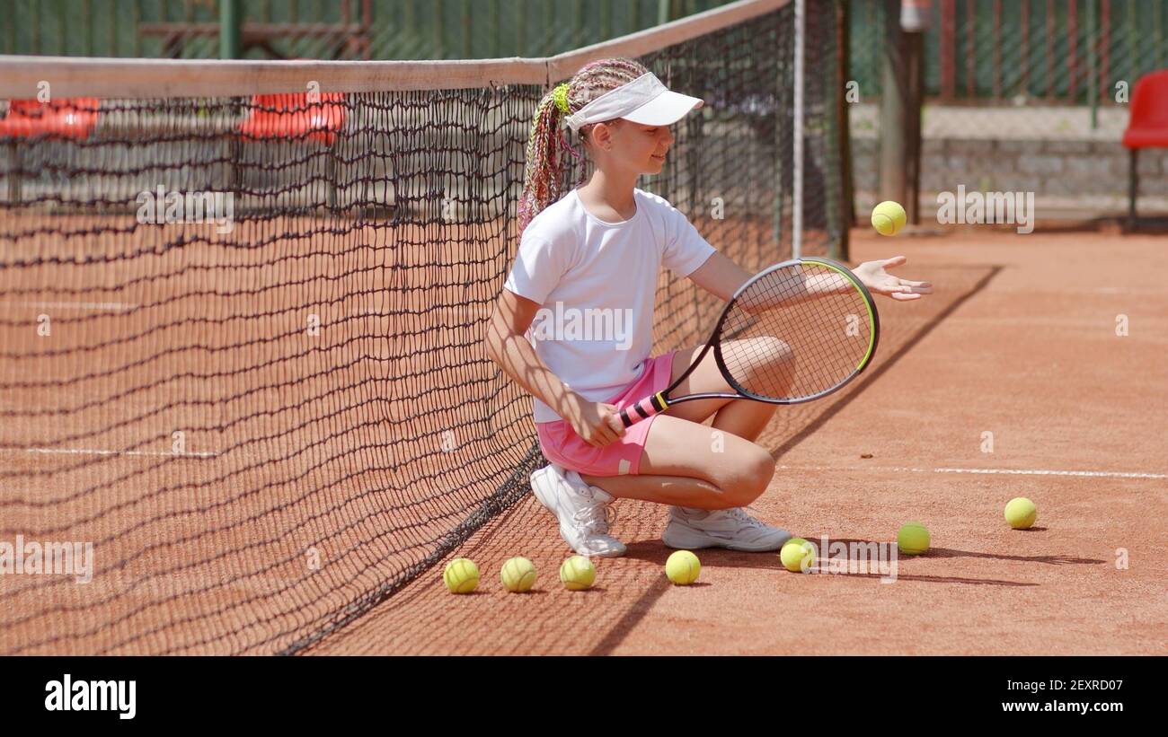 Girl tennis player sits on the court and throws balls Stock Photo Alamy