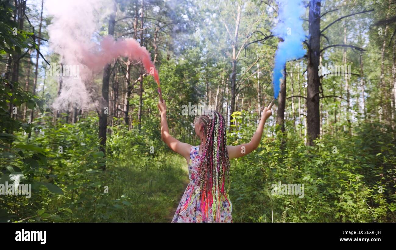 A teenage girl with blue smoke walks in the forest. Stock Photo