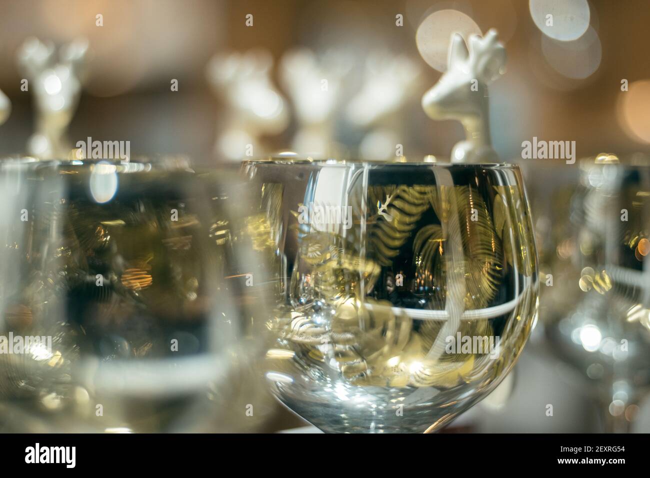 Closeup of a white ceramic deer spoons design hanging on a glass with beautiful soft bokeh in the background, copy space festive image of stag shaped Stock Photo