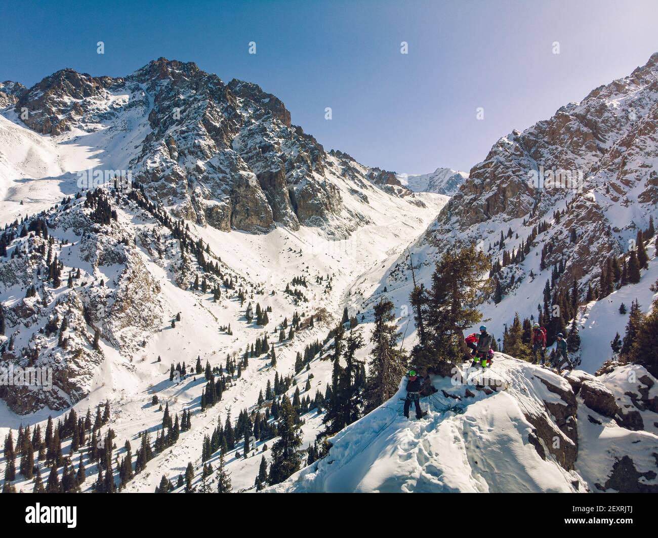 Almaty Region, Kazakhstan - FEBRUARY 28, 2021: Climbers on the top of a small rock. Winter training of climbers in the mountains. Mountaineering schoo Stock Photo