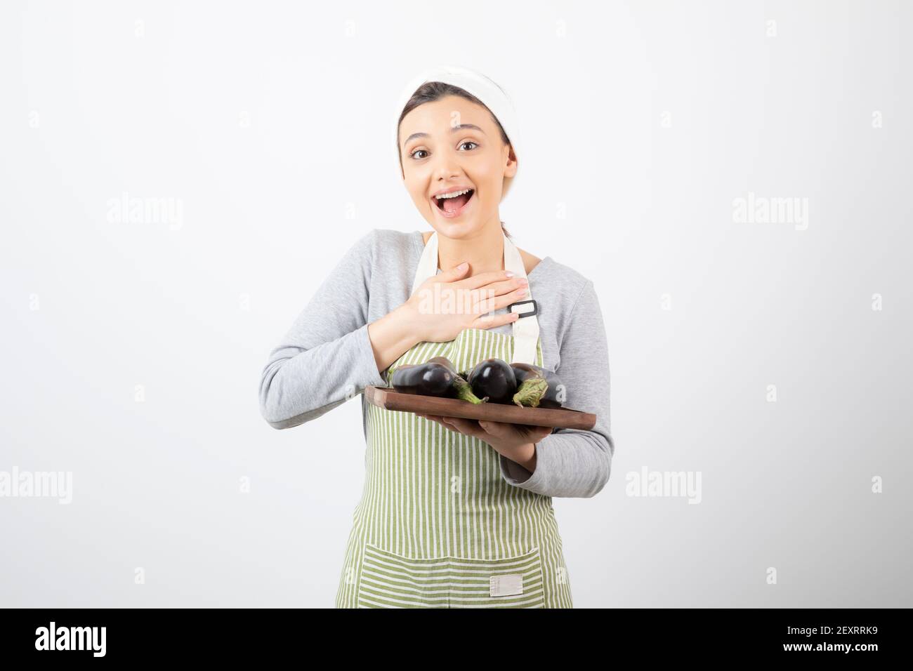 Photo of young female cook holding plate of eggplants and laughing Stock Photo
