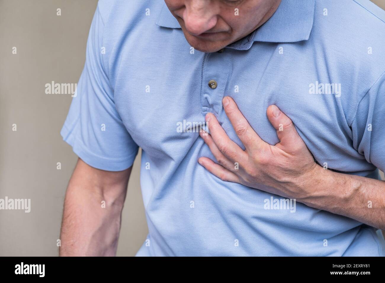 Heart pain, a person grabbing the heart area with his hand, suffering from chest pain, having a heart attack or painful cramps, pressing on the chest Stock Photo