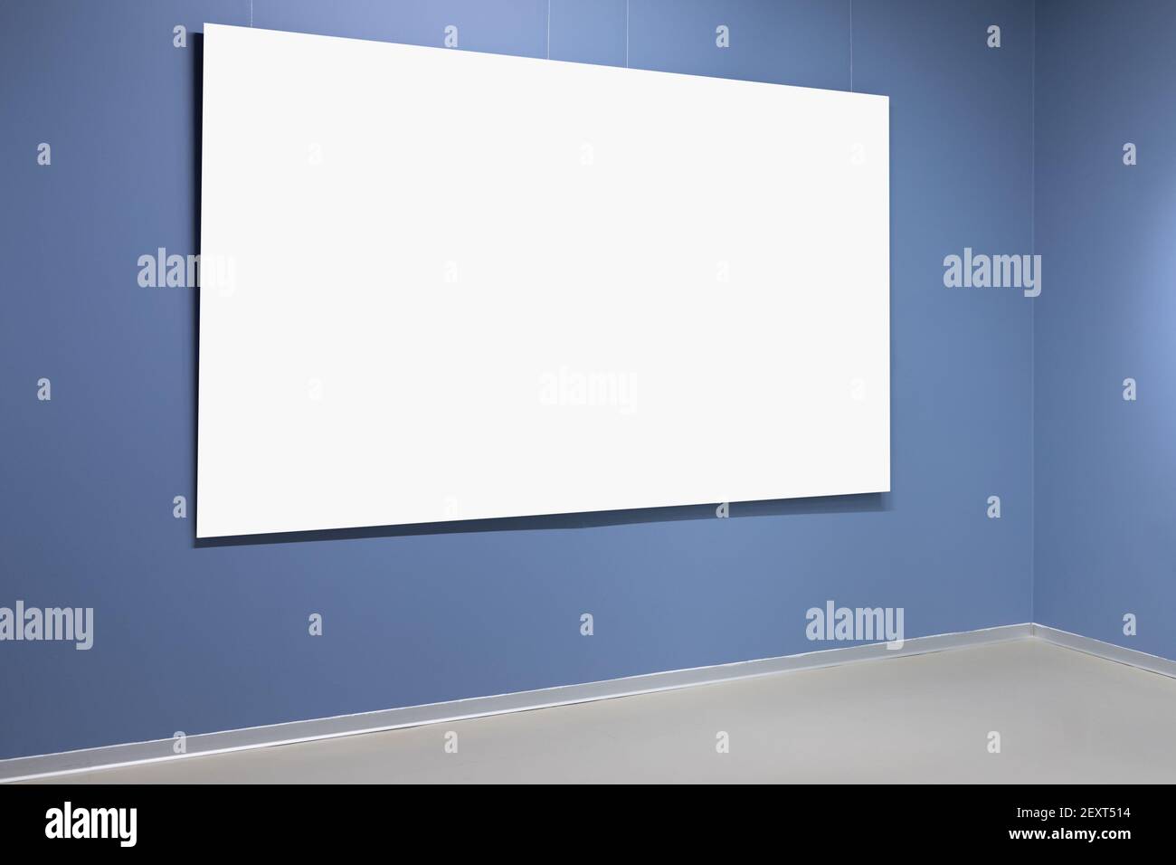 Blank white poster with copy space area is in corner of blue walls. Background photo template Stock Photo