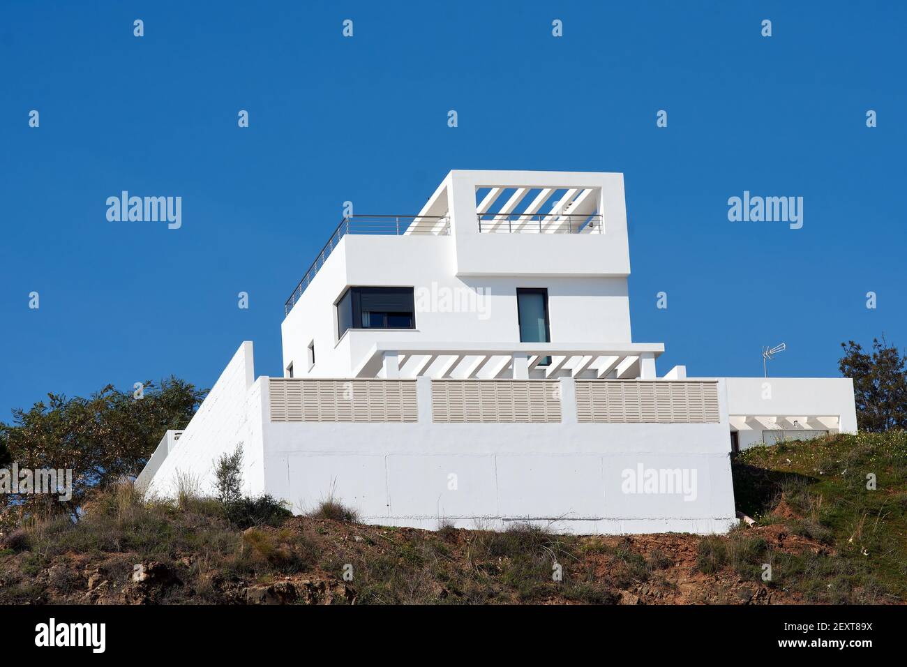 A white modernized house in the mountain under a clear blue sky background Stock Photo