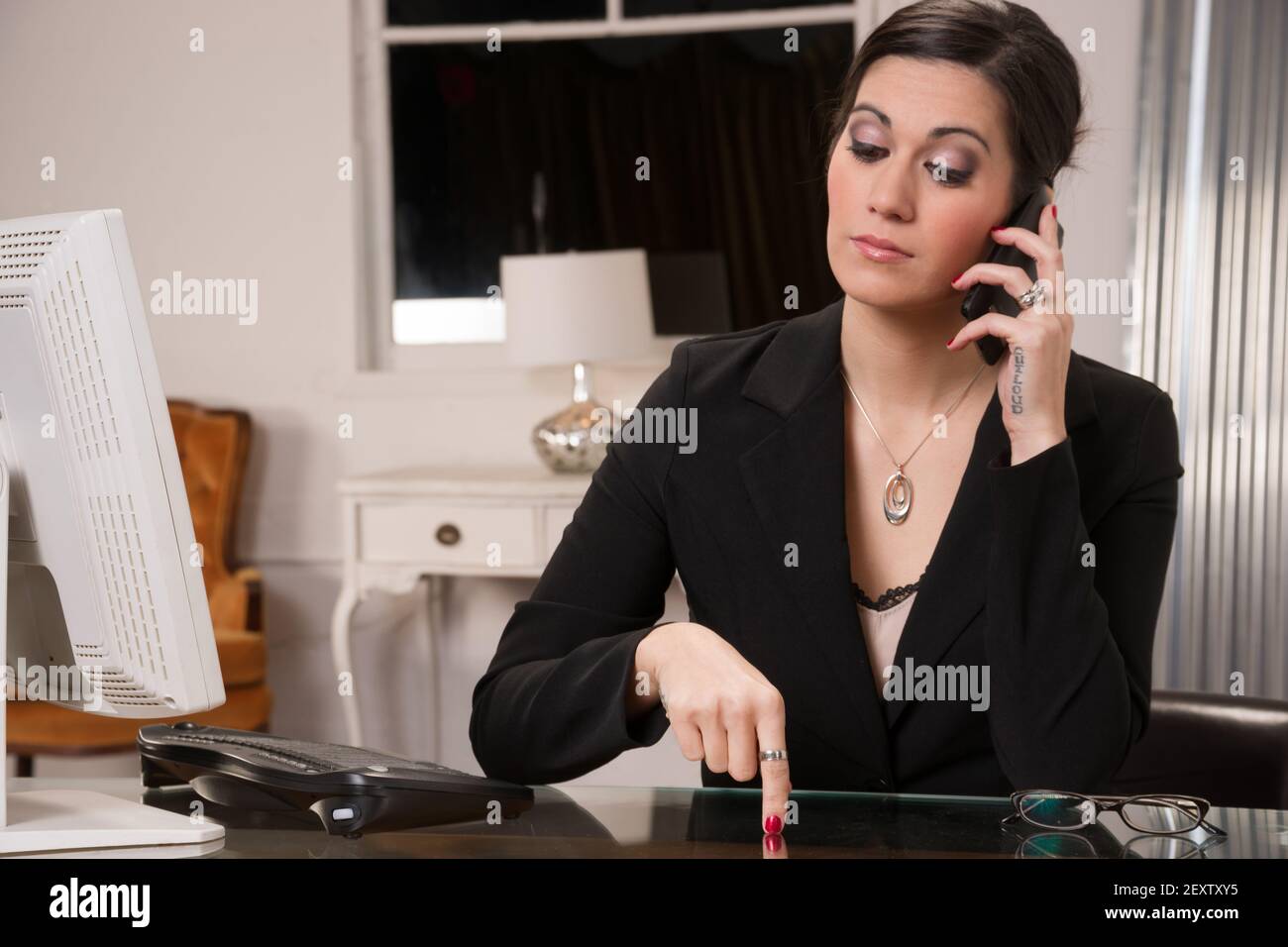 Business Woman in Adversarial Conversation Computer Desk Cell Phone Stock Photo