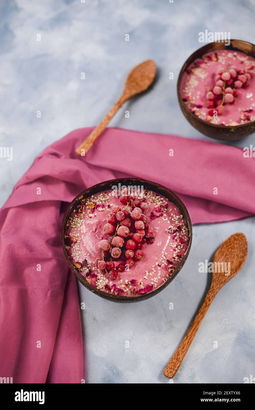 Two coconut bowls with currant yogurt and sesame seeds, topped with frozen currants Stock Photo