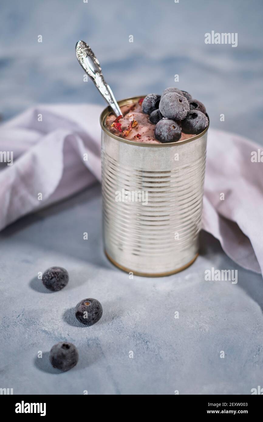 Tin can with currant yogurt and frozen blueberries Stock Photo