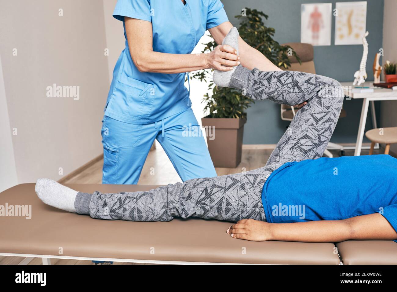 Physiotherapist doing treatment exercise for child's knee, close-up. Traumatologist's office Stock Photo