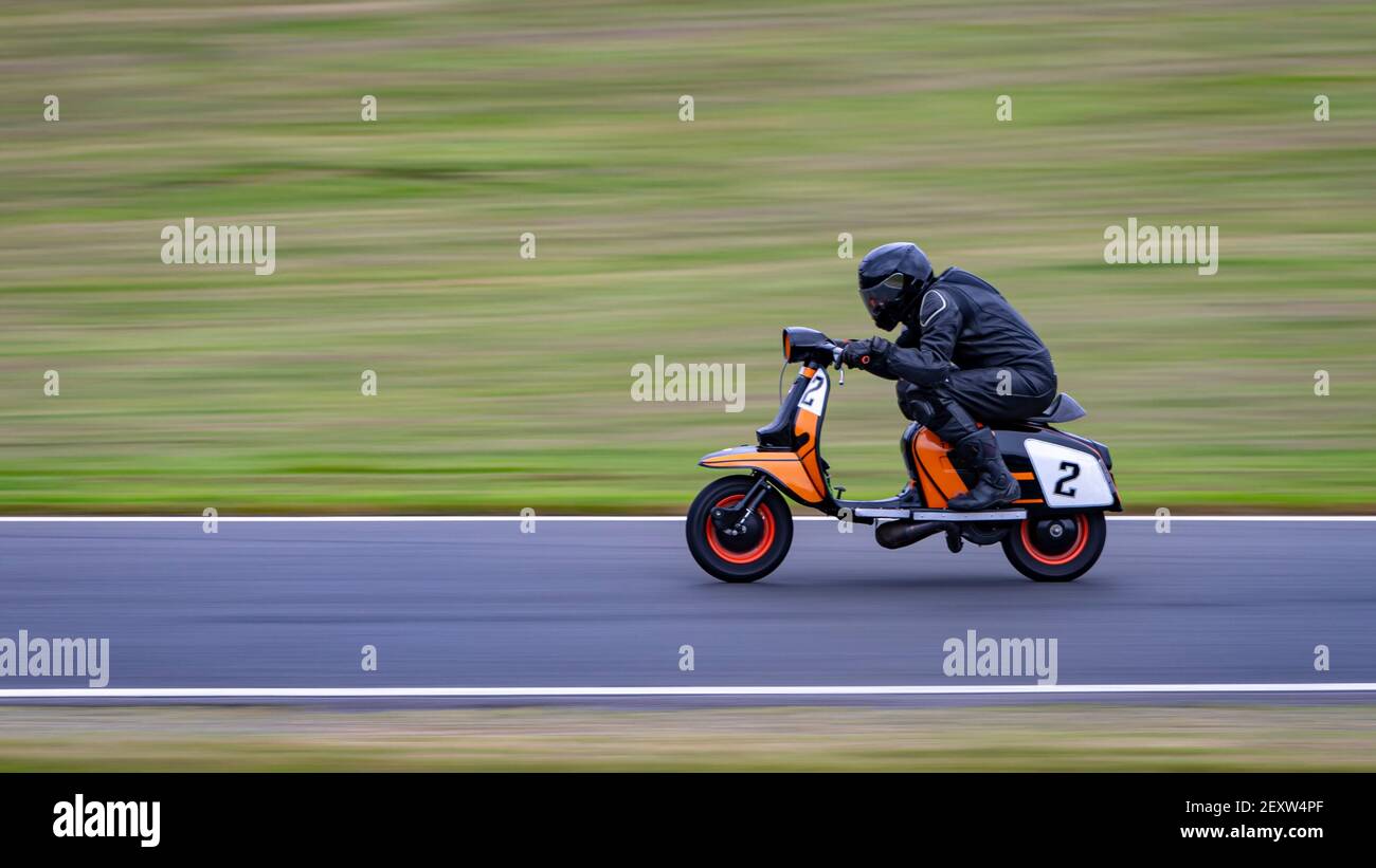 A panning shot of a racing moped as it circuits a track. Stock Photo