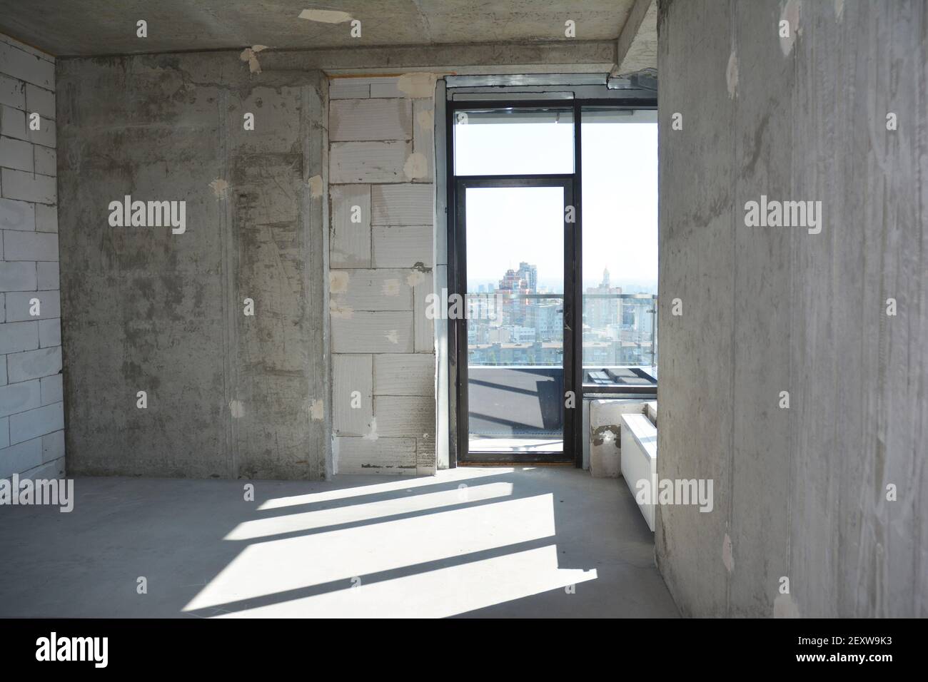 An inside view of an empty newly constructed apartment, flat without repair with a window installed in a newly built, erected residential building. Stock Photo