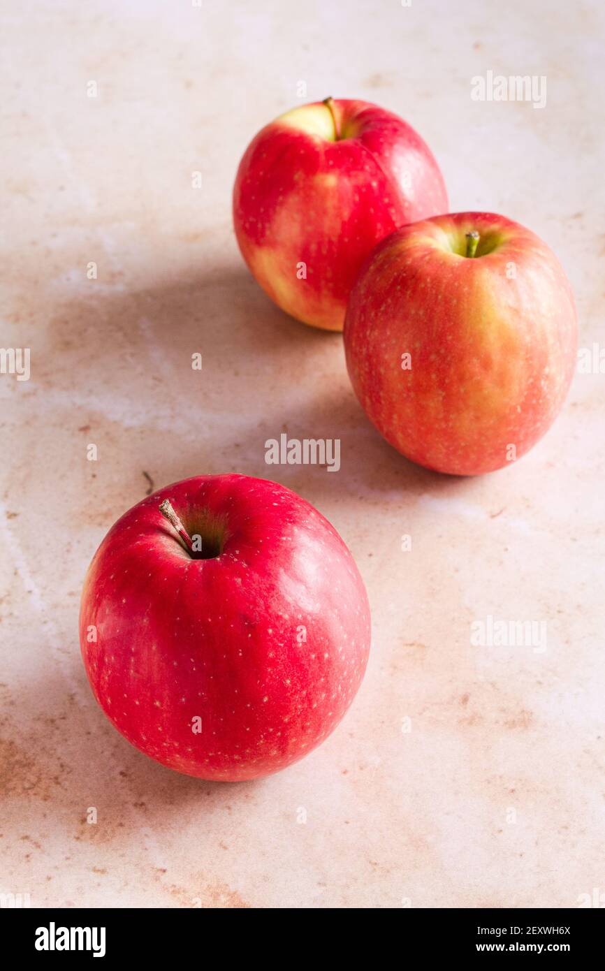 Three Pink Lady apples on a pink marble backdrop. Stock Photo