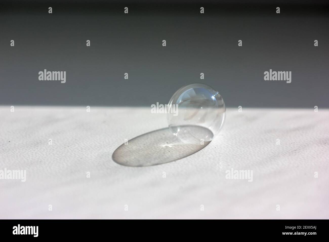 Soap bubble on the white table close-up. Contrasting shadow from a soap bubble.  Stock Photo