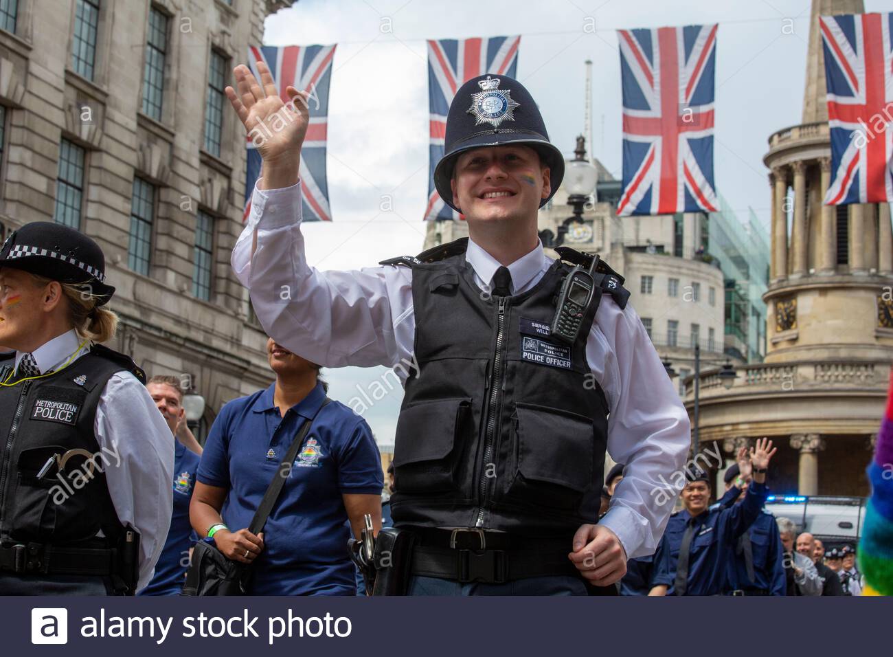 A policeman waves to the crowd during a Pride parade in London Stock Photo