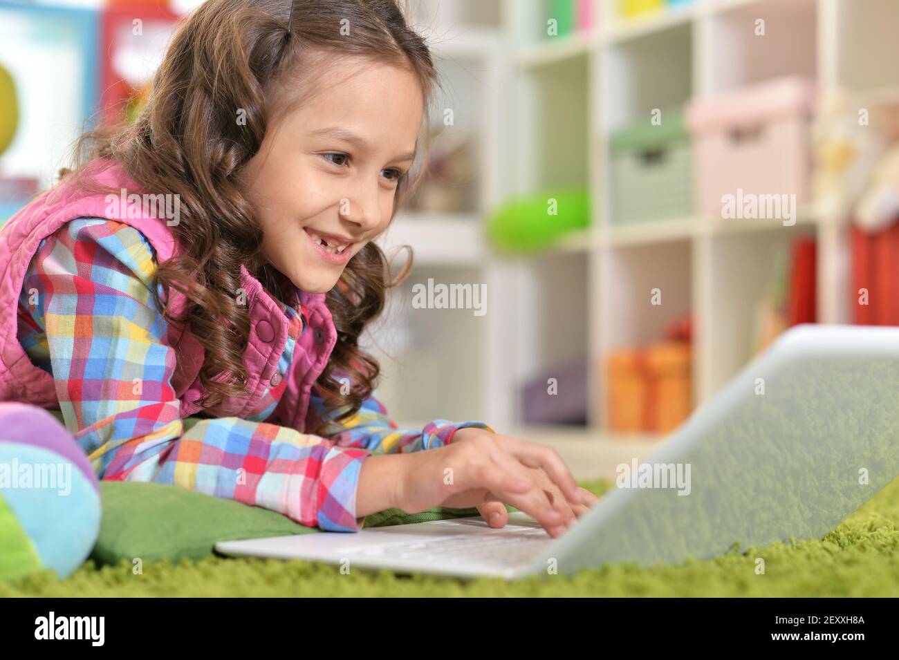 Cute girl using laptop while lying on green floor Stock Photo - Alamy